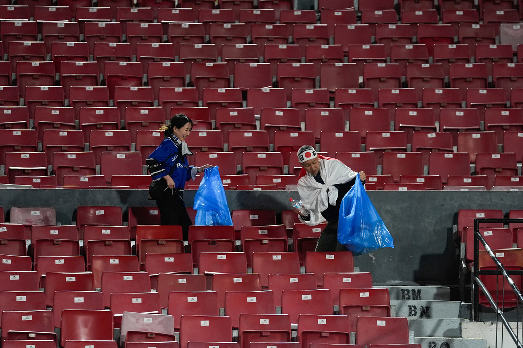 FILE - Japan fans clean up trash from the stands after a FIFA U-20 World Cup Group A soccer match against Chile at National Stadium in Santiago, Chile, on Sept. 30, 2025. (AP Photo/Matias Delacroix, File)