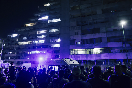 People gather in front of a building where a pedestrian walkway in a massive housing project collapsed in the southern Italian city of Naples, Tuesday, 23,2024, killing two people and injuring a dozen others. The collapse overnight involved an extended family, killing a 29-year-old male and 35-year-old woman, the news agency ANSA reported. Seven children ages 2 to 10 were among the injured, two of whom were in intensive care. (Alessandro Garofalo/LaPresse via AP)