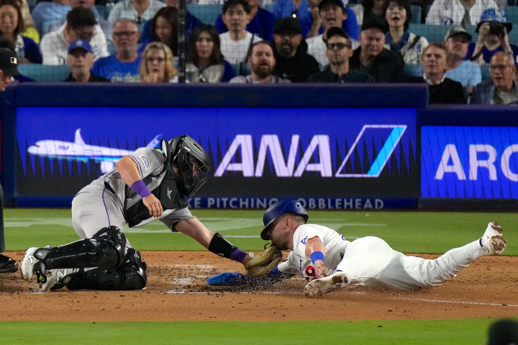 Los Angeles Dodgers' Dalton Rushing, right, is tagged out by Colorado Rockies catcher Braxton Fulford as he tries to score on a fielder's choice bunt by Miguel Rojas during the fifth inning of a baseball game Tuesday, July 7, 2026, in Los Angeles. (AP Photo/Mark J. Terrill)