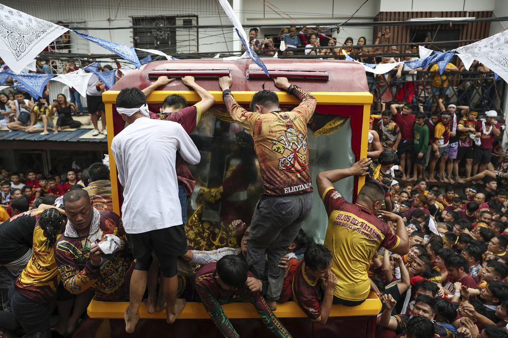 Devotees try to climb on a glass-covered carriage carrying the image of Jesus Nazareno during its annual procession in Manila, Philippines Thursday, Jan. 9, 2025. (AP Photo/Basilio Sepe)