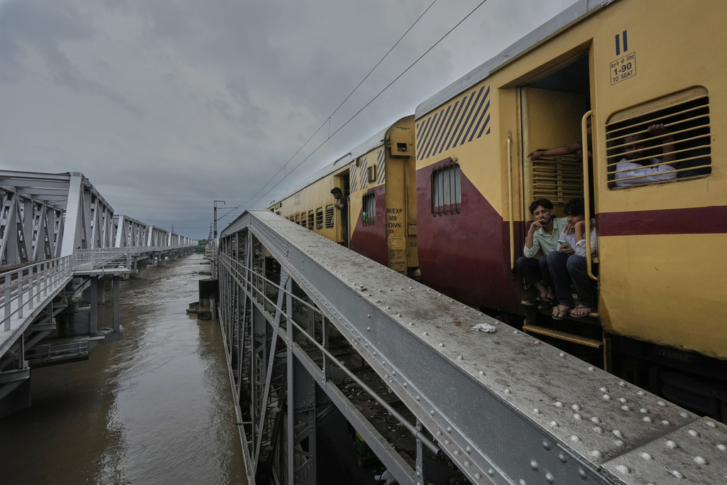 A passenger train crosses a bridge over the swollen Yamuna River in New Delhi, India, Tuesday, Sept. 2, 2025. (AP Photo/Manish Swarup)
