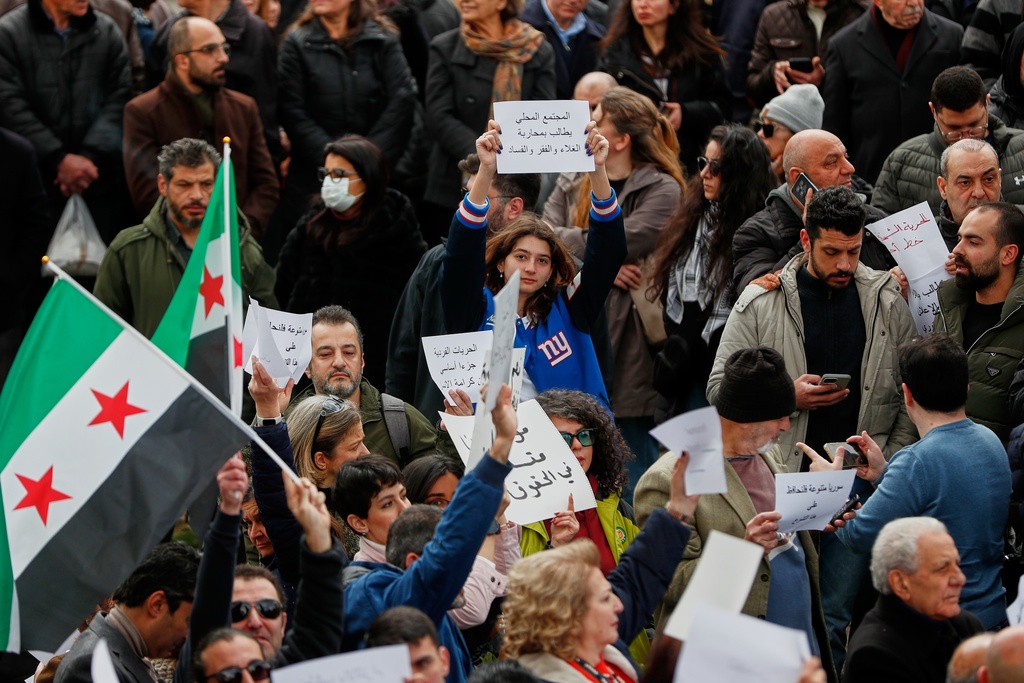 Protesters hold signs during a demonstration against against new alcohol restrictions that limit sales largely to Christian areas in Damascus, Syria, Sunday, March 22, 2026.(AP Photo/Omar Sanadiki)