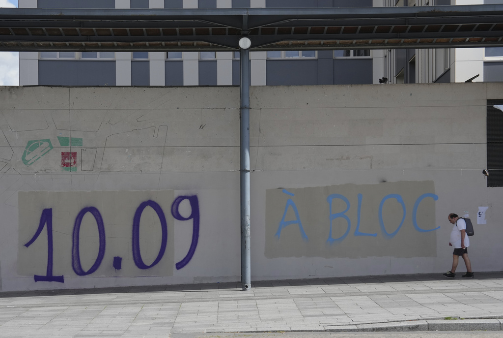 A man walks past a graffiti that reads, "September 10, all-out strike" in Paris, Tuesday, Sept. 9, 2025, at the eve of a national protest. (AP Photo/Aurelien Morissard)