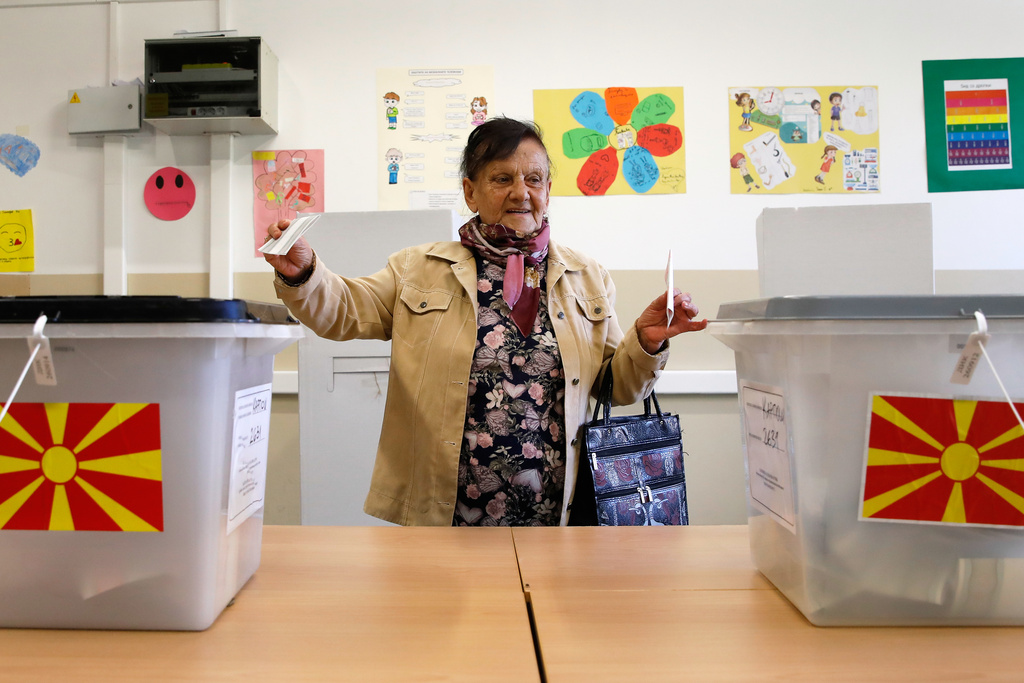 A woman holding her ballots walks to the ballot boxes during the runoff local elections, at a polling station in Skopje, North Macedonia, on Sunday, Nov. 2, 2025. (AP Photo/Boris Grdanoski)