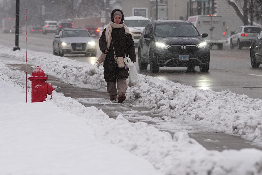 A pedestrian walks on a snow-covered sidewalk in Wheeling, Ill., Monday, Dec. 1, 2025. (AP Photo/Nam Y. Huh)