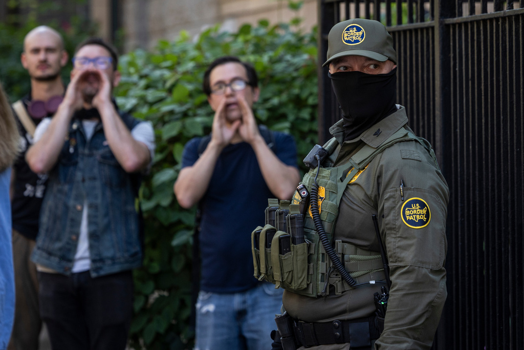 Pedestrians chant, "ICE go home!" as federal immigration agents stand on North Clark Street near West Oak Street in the River North neighborhood, Sunday, Sept. 28, 2025, in Chicago. (Ashlee Rezin/Chicago Sun-Times via AP)