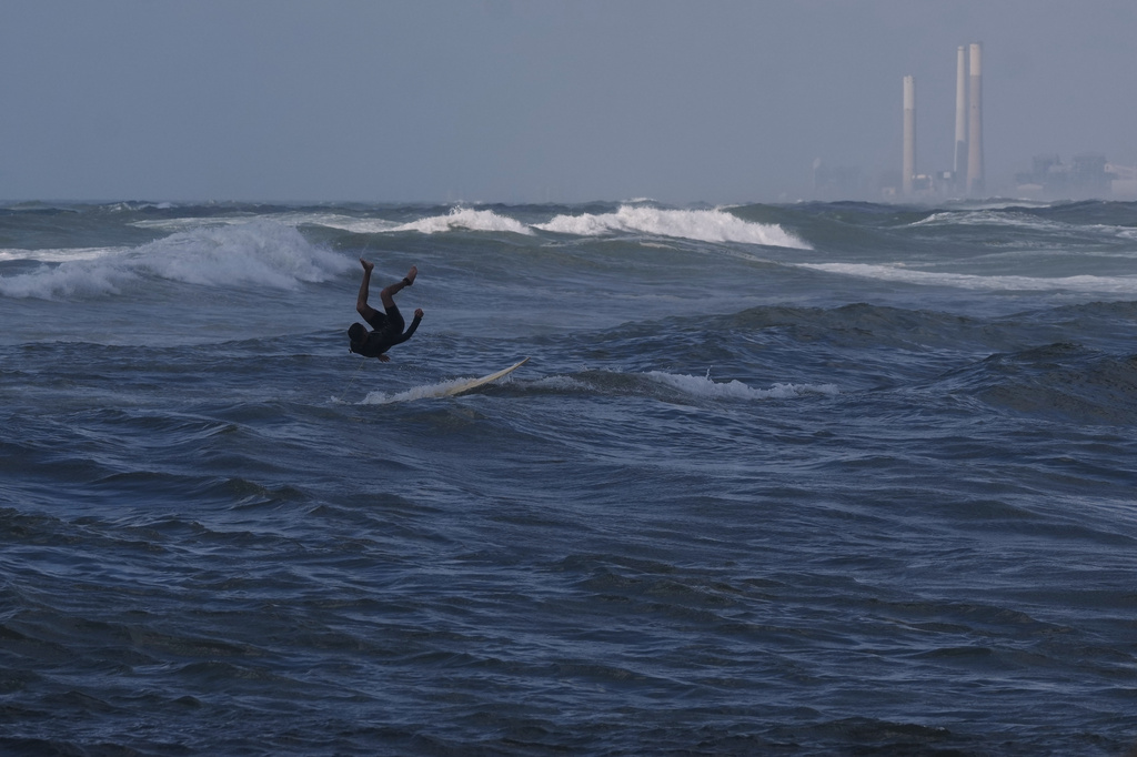 A Palestinian jumps into the waters of the Mediterranean Sea as he surfs on the beach in Gaza City, Monday, May 4, 2026. (AP Photo/Jehad Alshrafi)