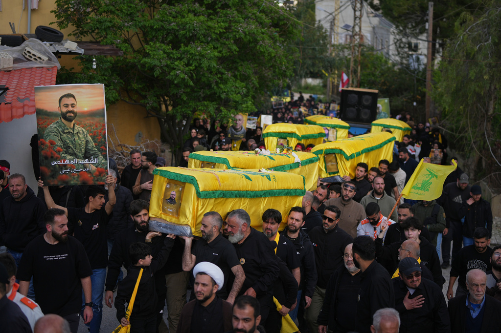 Mourners carry the coffins of Hezbollah fighters killed before the ceasefire in the war between Hezbollah and Israel during a mass funeral procession in the southern village of Kfar Sir, Lebanon, Tuesday, April 21, 2026. (AP Photo/Hassan Ammar)