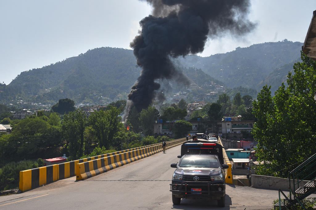 A police vehicle is parked at along a road as smoke billows after an army MI-17 helicopter crashed due to a technical fault, in Muzaffarabad, capital of Pakistan-administered Kashmir, Wednesday, June 10, 2026. (AP Photo/M.D. Mughal)