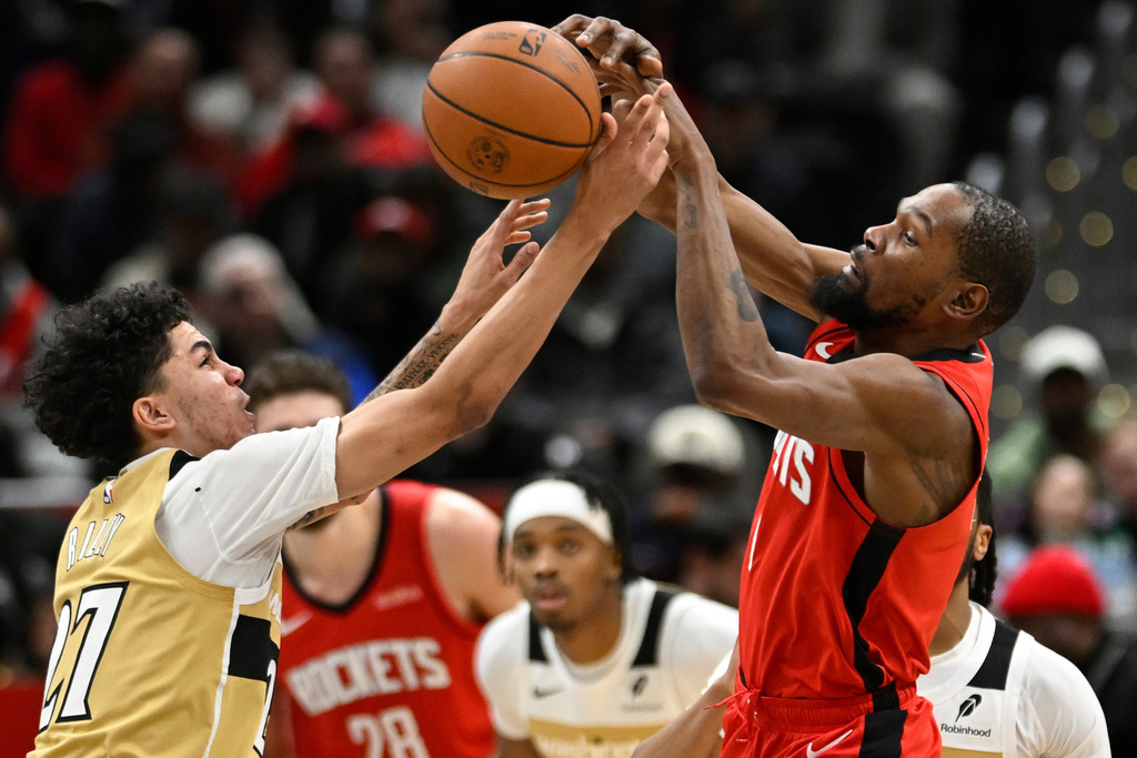 Washington Wizards guard Will Riley, left, and Houston Rockets forward Kevin Durant, right, compete the ball during the second half of an NBA basketball game, Monday, March 2, 2026, in Washington. (AP Photo/John McDonnell)