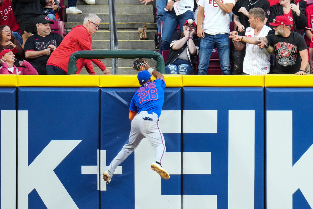 New York Mets outfielder Cedric Mullins (28) attempts to catch a solo home run hit by Cincinnati Reds' Matt McLain during the third inning of a baseball game, Saturday, Sept. 6, 2025, in Cincinnati. (AP Photo/Jeff Dean)
