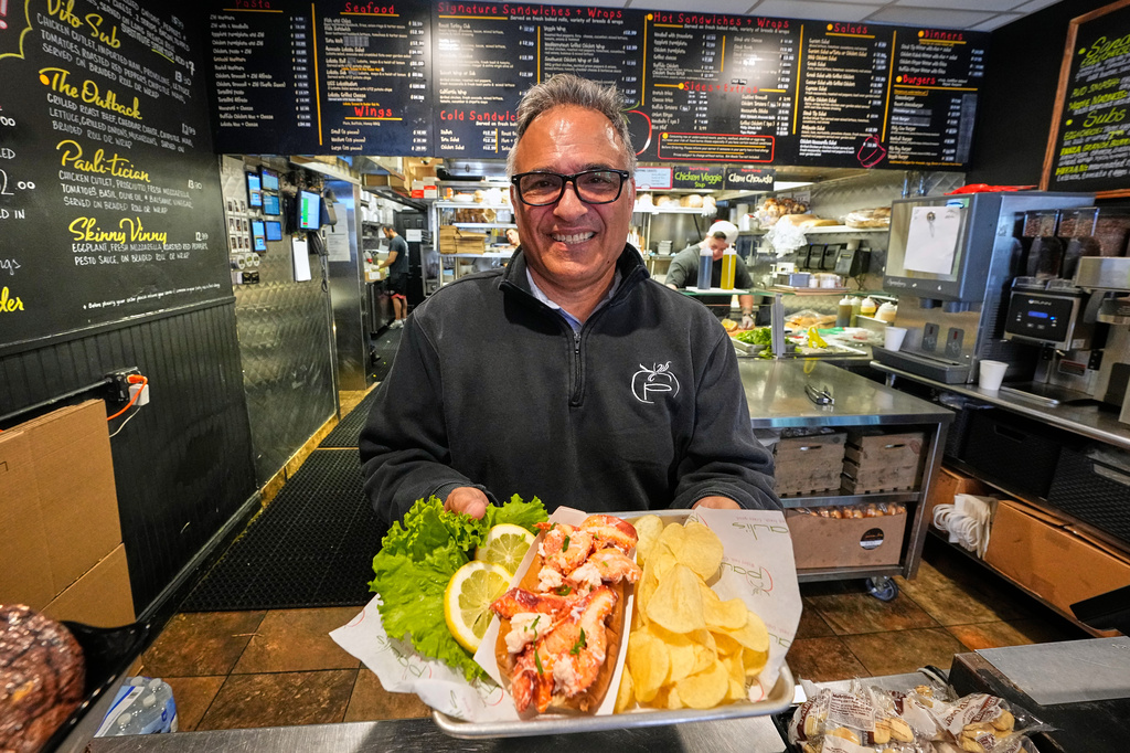 Principal Paul Barker serves lobster rolls to World Cup tourists at Pauli's sandwich shop in the North End of Boston, Wednesday, June 24, 2026. (AP Photo/Martin Meissner)