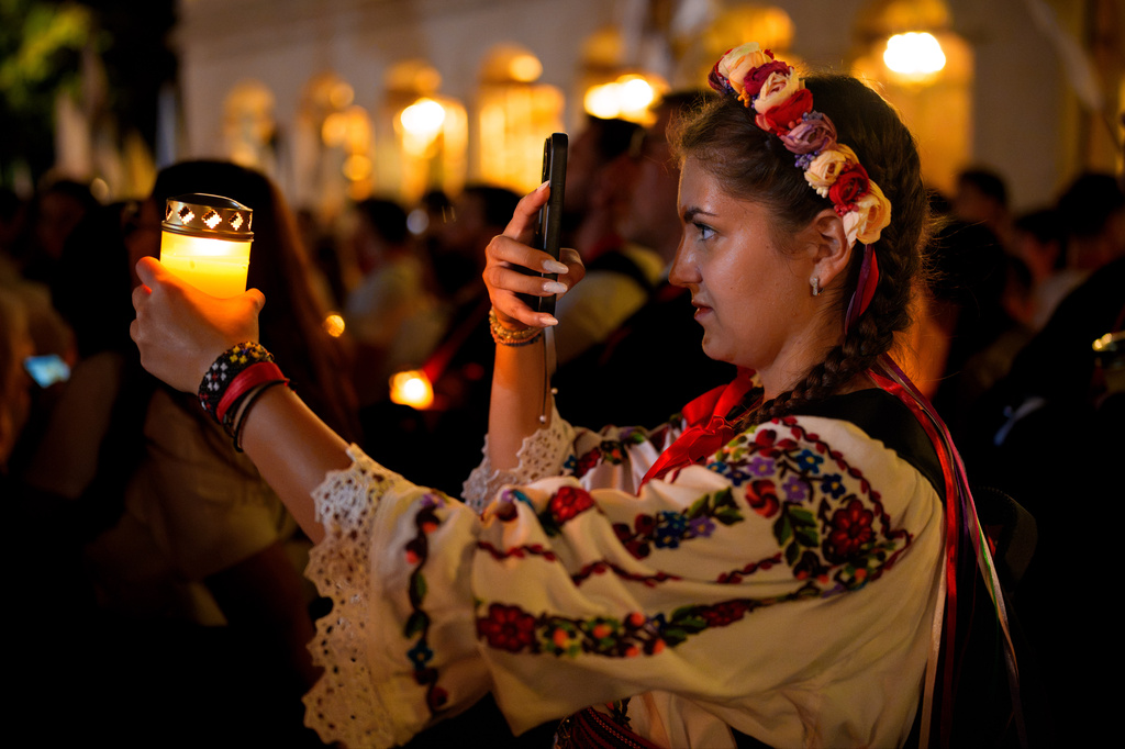 A young woman takes pictures of a candle, outside the Patriarchal Cathedral at the end of the Procession of Lights, part of a four-day program of the International Meeting of Orthodox Youth (ITO), in Bucharest, Romania, Wednesday, Sept. 2, 2026. (AP Photo/Andreea Alexandru)