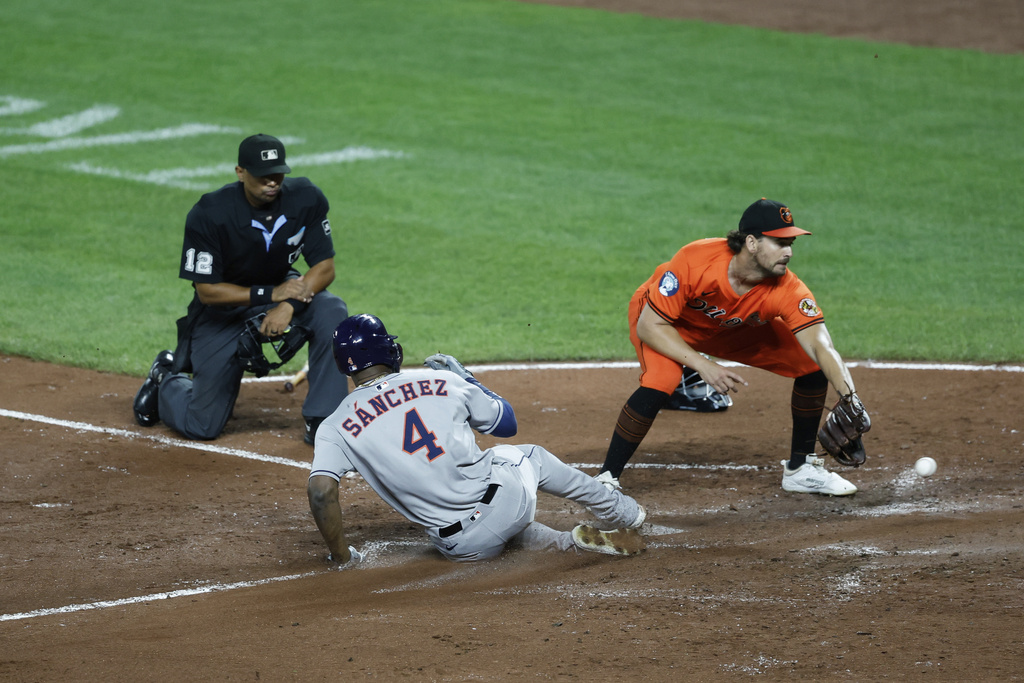 Houston Astros' Jesús Sánchez (4) avoids the tag from Baltimore Orioles pitcher Dean Kremer scores a on throwing error by first baseman Coby Mayo during the third inning of a baseball game, Saturday, Aug. 23, 2025, in Baltimore. (AP Photo/Terrance Williams)