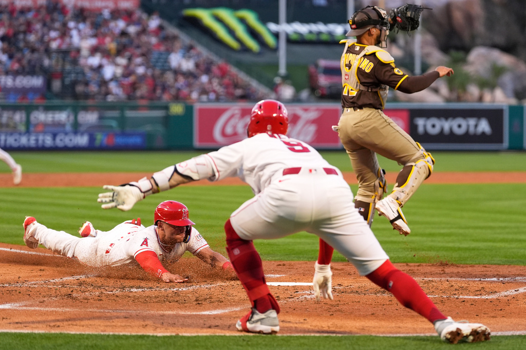 Los Angeles Angels' Logan O'Hoppe, left, scores on a double by Adam Frazier as Zach Neto, center, gestures and San Diego Padres catcher Luis Campusano takes a late throw during the second inning of a baseball game Friday, April 17, 2026, in Anaheim, Calif. (AP Photo/Mark J. Terrill)