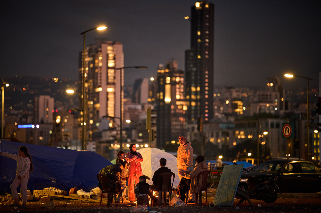 A family who fled Israeli shelling in southern Lebanon warm themselves by a bonfire next to tents used as shelters in Beirut, Lebanon, Tuesday, March 31, 2026. (AP Photo/Emilio Morenatti)