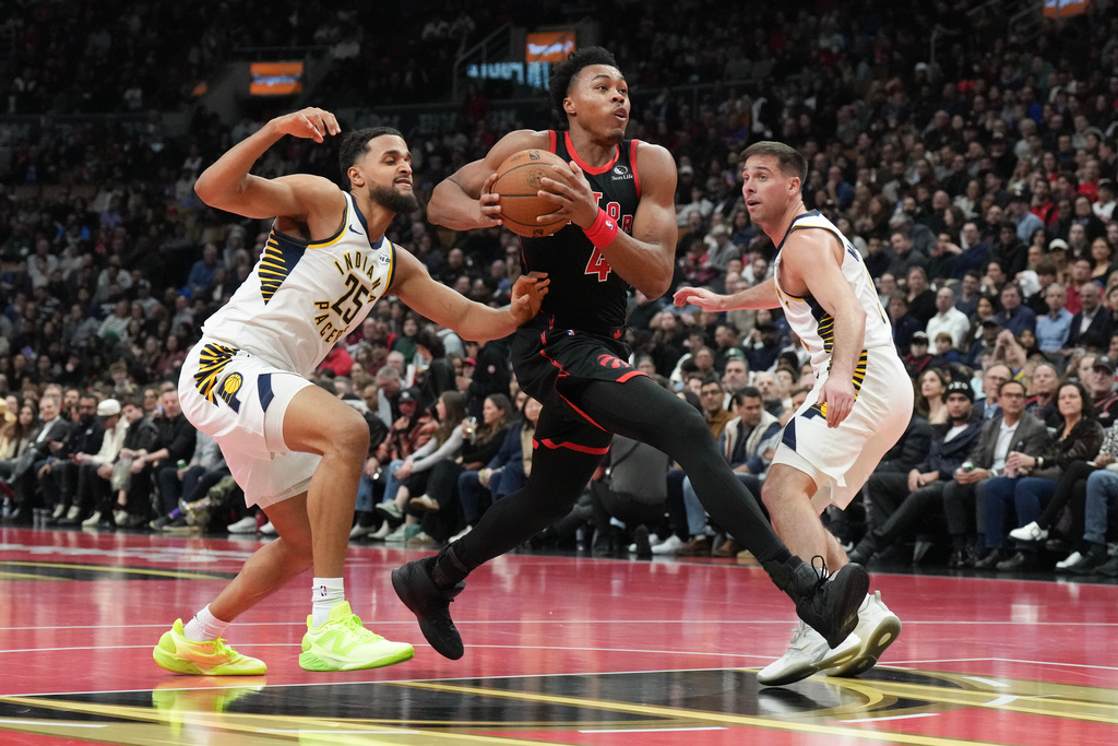 Toronto Raptors forward Scottie Barnes (4) drives to the net between Indiana Pacers forward Jeremiah Robinson-Earl (25) and guard T.J. McConnell (9) during first half NBA Cup basketball action in Toronto on Wednesday, Nov. 26, 2025. (Chris Young/The Canadian Press via AP)