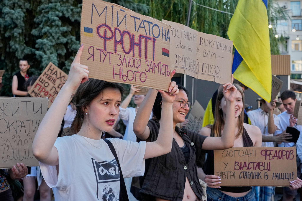 An activist holds slogan "My father is at the front. I am angry here on his behalf" during a rally to denounce President Volodymyr Zelenskyy's decision to dismiss Defense Minister Mykhailo Fedorov after six months in the post, Friday, July 17, 2026, Kyiv, Ukraine. (AP Photo/Efrem Lukatsky)