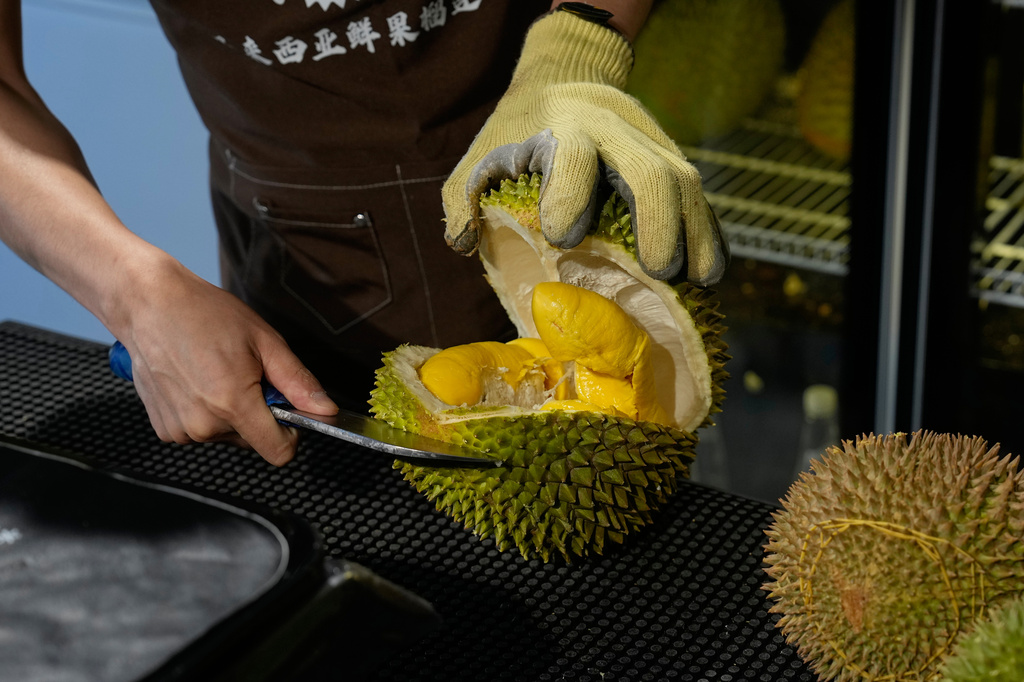 A worker opens durian fruits imported from Malaysia to pack and deliver for customer at a shop in Beijing, China, Monday, July 13, 2026. (AP Photo/Andy Wong)