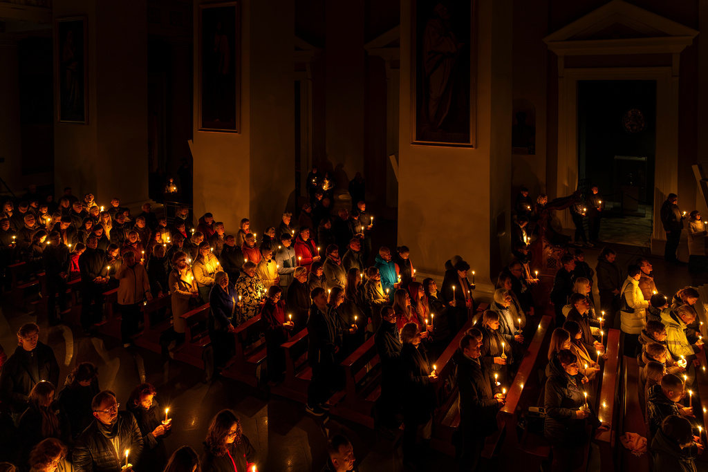 Worshippers hold candles during the Easter vigil Mass in the Cathedral Basilica of Vilnius, Lithuania, late Saturday, April 4, 2026. (AP Photo/Mindaugas Kulbis)