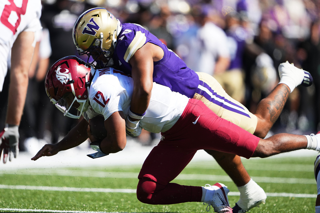 Washington linebacker Xe'ree Alexander tackles Washington State quarterback Caden Pinnick during the first half of an NCAA college football game, Sunday, Sept. 6, 2026, in Seattle. (AP Photo/Lindsey Wasson)