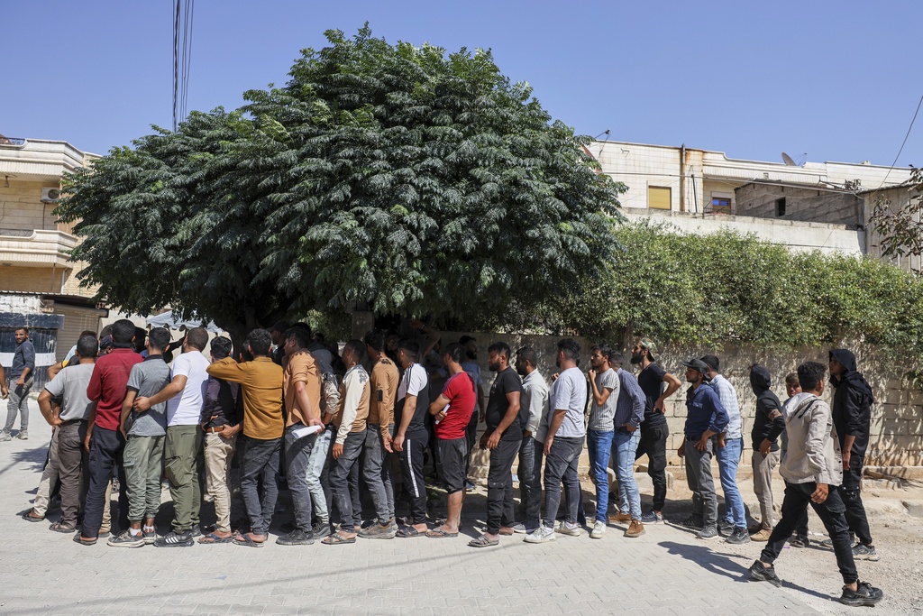 Young Kurdish men line up to sign up to join the Syrian government's General Security forces at a police station in Afrin, Syria, an area in the country's north from which Kurds were forcibly displaced years ago, Thursday Aug. 21, 2025. (AP Photo/Omar Albam)