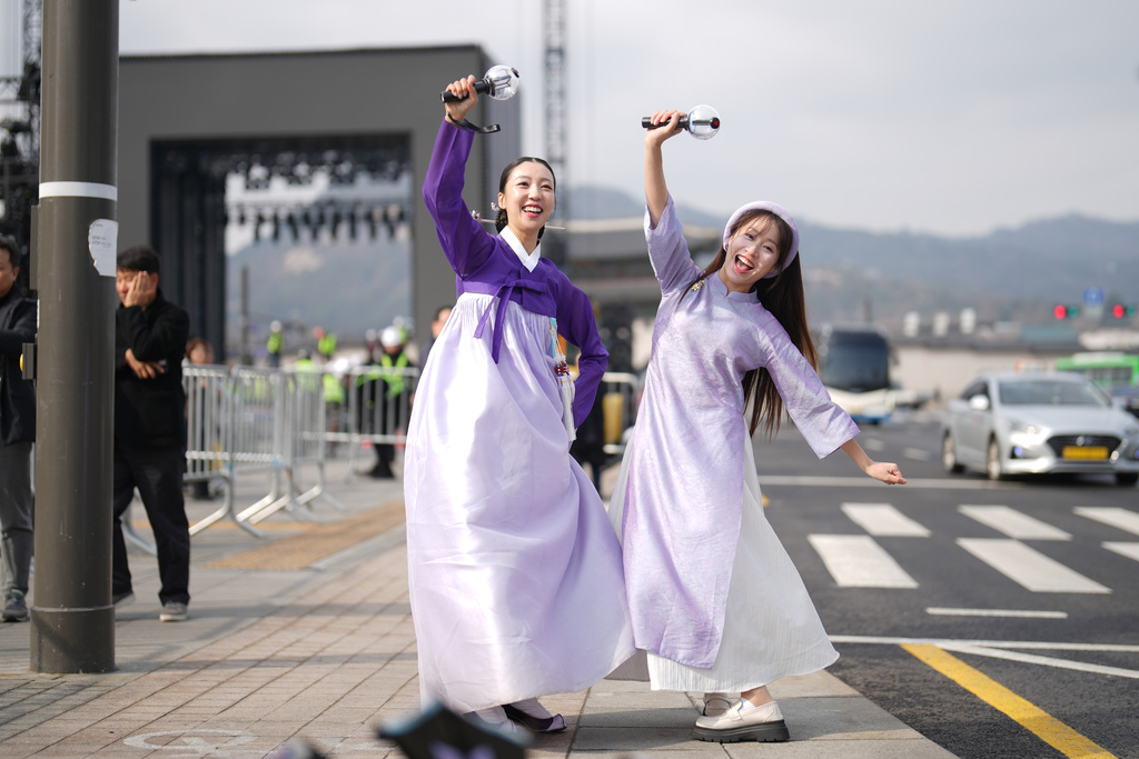 Fans of K-pop band BTS, South Korean Chaemin Shin, left, and Vietnamese Tam Tamie, right, and sing at Gwanghwamun Square in Seoul, South Korea, Wednesday, March 18, 2026. (AP Photo/Lee Jin-man)