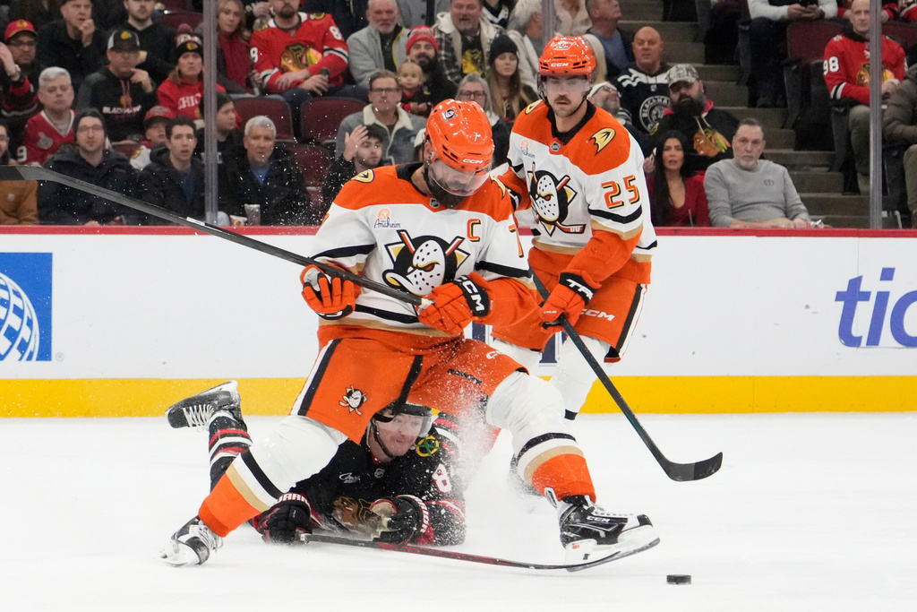 Chicago Blackhawks center Ryan Donato (8) and Anaheim Ducks defenseman Radko Gudas (7) fight for the puck during the first period of an NHL hockey game Sunday, Nov. 30, 2025, in Chicago. (AP Photo/David Banks)