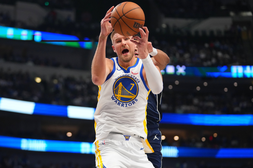 Golden State Warriors center Kristaps Porzingis (7) competes for a rebound against Dallas Mavericks guard Max Christie during the first half of an NBA basketball game Monday, March 23, 2026, in Dallas. (AP Photo/Julio Cortez)