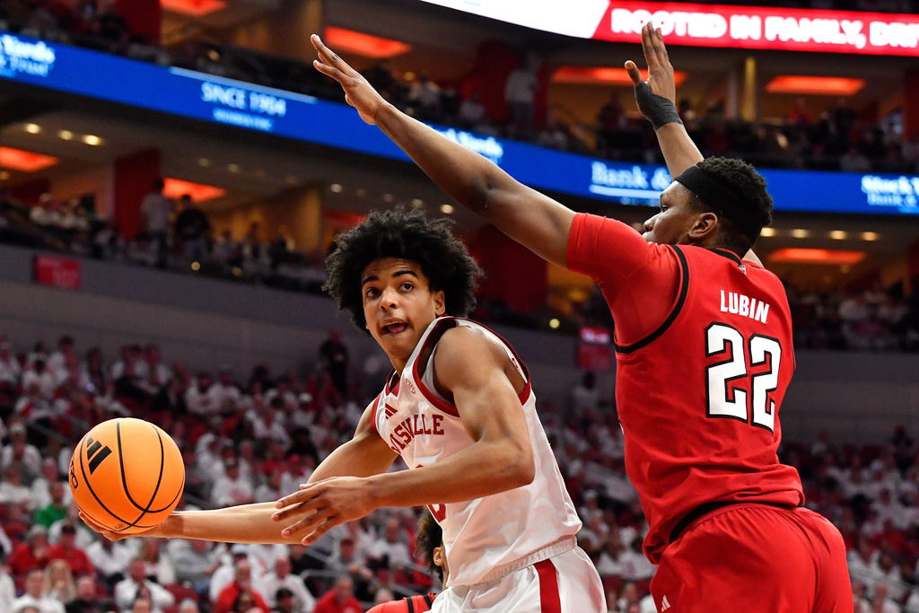 Louisville guard Mikel Brown Jr., left, passes the ball away from North Carolina State forward Ven-Allen Lubin (22) during the second half of an NCAA college basketball game in Louisville, Ky., Monday, Feb. 9, 2026. (AP Photo/Timothy D. Easley)