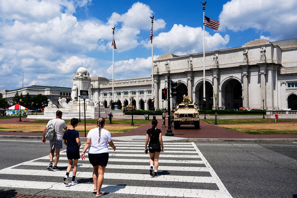 FILE - People walk to Union Station as District of Columbia National Guard soldiers stand outside their M-ATV, Aug. 16, 2025, in Washington. (AP Photo/Julia Demaree Nikhinson, File)