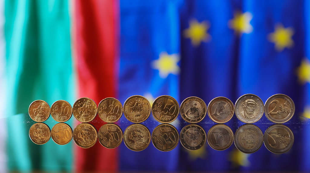 New Euro coins with Bulgarian symbols reflected in a table seen backdropped by Bulgarian and EU flag, Sofia, Tuesday Dec. 30, 2025. (AP Photo/Valentina Petrova)