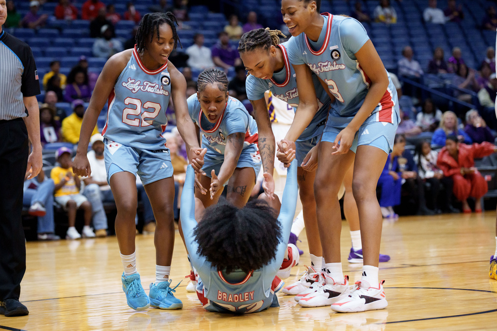 Louisiana Tech guard Paris Bradley (23) gets helped up by teammates after drawing a charge against LSU during the first half of an NCAA college basketball game Saturday, Dec. 13, 2025, in New Orleans. (AP Photo/Matthew Hinton)