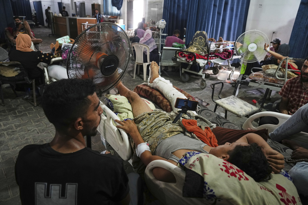 Palestinian patients seek relief from the heat by sitting near a fan during a heat wave, inside a warehouse set up in the yard of Shifa Hospital in Gaza City, Wednesday, Aug. 13, 2025. (AP Photo/Jehad Alshrafi)