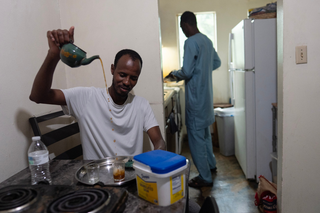 Moussa Diallo, left, makes traditional Mauritanian green tea as Khalidou Sow prepares lamb in the kitchen of their shared apartment in Lockland, Ohio, Friday, July 17, 2026. (AP Photo/Carolyn Kaster)