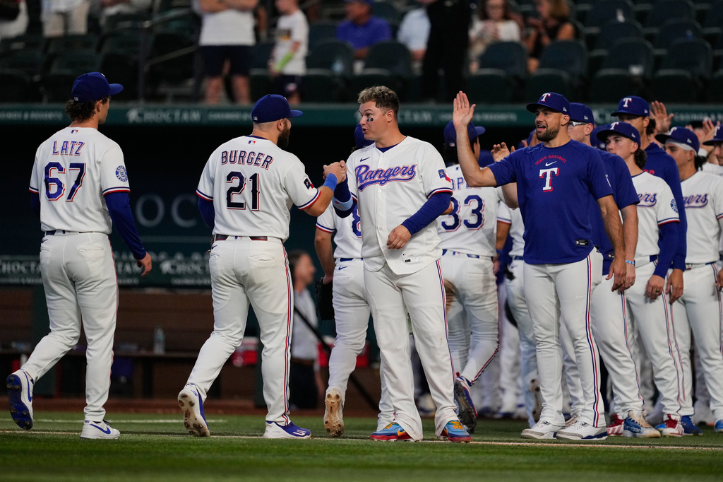 Texas Rangers' Jacob Latz (67), Jake Burger (21), Joc Pederson, center, Nathan Eovaldi, right and the rest of the team celebrate their win against the Seattle Mariners in a baseball game in Arlington, Texas, Monday, July 27, 2026. (AP Photo/Tony Gutierrez)