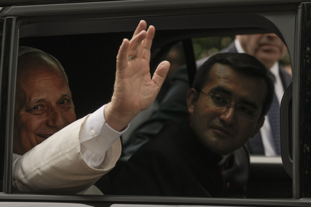 Pope Leo XIV waves from his car as he leaves with his personal secretary, Monsignor Edgard Iván Rimaycuna Inga, right, after visiting the Città Universitaria (University City) at Sapienza University of Rome where he met with faculty and students at the institution's primary campus, one of the world's oldest and largest universities, Thursday, May 14, 2026. (AP Photo/Gregorio Borgia)