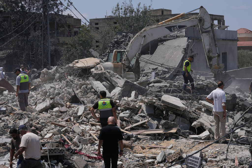 People and rescue workers gather on a destroyed house that was hit by an Israeli airstrike in Deir al-Zahrani village, southern Lebanon, Saturday, Aug. 15, 2026. (AP Photo/Mohammed Zaatari)