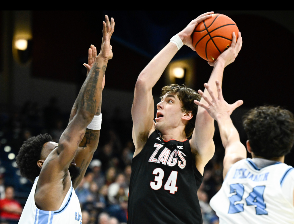 Gonzaga forward Braden Huff (34) goes up to shoot between San Diego forward Tim Moore (30), left, and Brandon Benjamin (24) during the first half of an NCAA college basketball game Tuesday, Dec. 30, 2025, in San Diego. (AP Photo/Denis Poroy)
