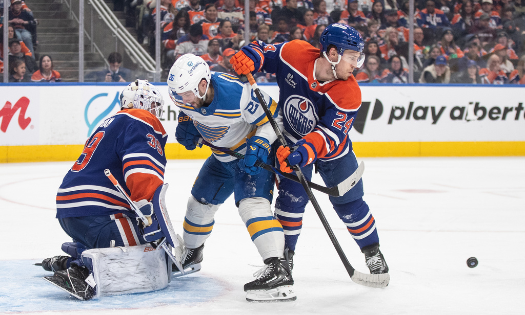 St. Louis Blues' Nathan Walker (26) and Edmonton Oilers' Spencer Stastney (24) battle on front as goalie Connor Ingram (39) makes the save during third period NHL hockey action, in Edmonton on Sunday, Jan. 18, 2026. (Jason Franson/The Canadian Press via AP)