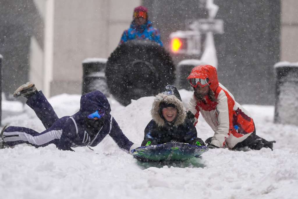Jack Wilson, center, sleds down a street in lower Manhattan during a snow storm, Monday, Feb. 23, 2026, in New York. (AP Photo/Seth Wenig)
