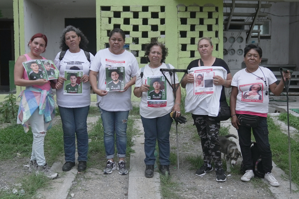 Relatives of missing people pose with posters of their loved ones wearing Mexican national soccer team jerseys and styled as World Cup sticker album cards during one of their weekly searches for missing relatives at an abandoned property on the outskirts of Guadalajara, Mexico, Tuesday, June 16, 2026. (AP Photo/Martin Silva)