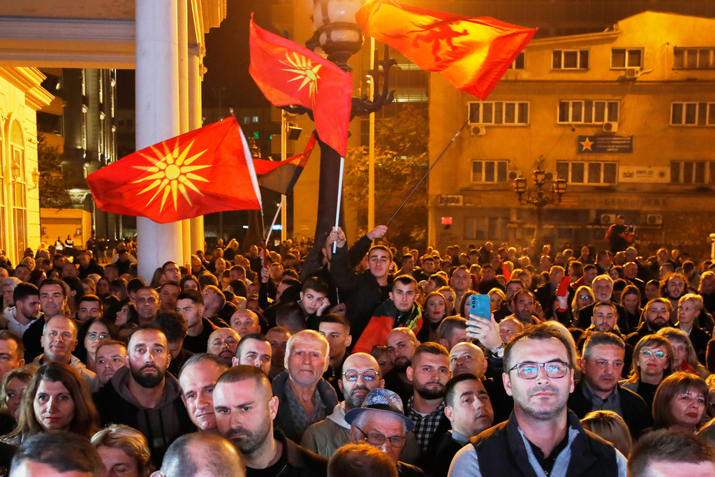 Supporters of the conservative VMRO-DPMNE party wave party flags and the old national flag as the leader Hristijan Mickoski announces a "great" victory in the local elections, at the party headquarters in Skopje, North Macedonia, on Sunday, Nov. 2, 2025. (AP Photo/Boris Grdanoski)