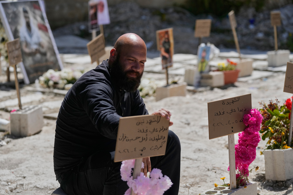 Hussein Farran whose six members of his family were killed in a Israeli airstrike in Kfar Hatta village, visits their graves at a cemetery where civilians and Hezbollah fighters are temporary buried in the southern port city of Sidon, Lebanon, Tuesday, April 14, 2026. (AP Photo/Mohammed Zaatari)