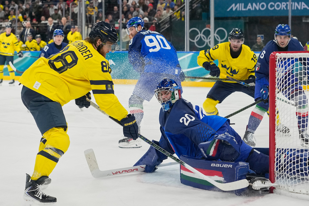 Italy's goalkeeper Damian Clara (20) makes a save against Sweden's William Nylander (88) during a preliminary round match of men's ice hockey between Italy and Sweden at the 2026 Winter Olympics, in Milan, Italy, Wednesday, Feb. 11, 2026. (AP Photo/Hassan Ammar)