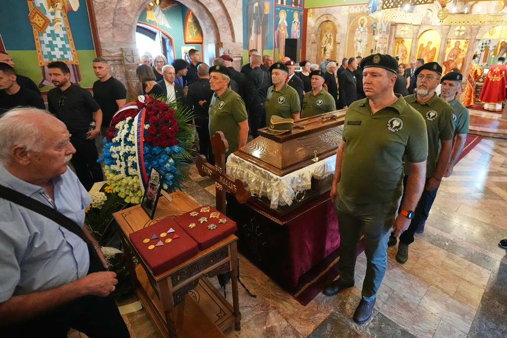 People line up to pay their respects as Serbian war veterans stand around the coffin of the former Bosnian Serb army commander Ratko Mladic, who died last week while serving a life sentence for genocide and other atrocities during the war in Bosnia, at the St. Luka Church, in Belgrade, Serbia, Monday, Sept. 7, 2026. (AP Photo/Darko Vojinovic)