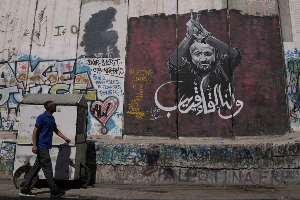 FILE - A man walks past a mural depicting the Palestinian leader Marwan Barghouti, with a message that reads in Arabic, "See you soon,” on Israel's separation barrier in the West Bank city of Bethlehem, Aug. 20, 2025. (AP Photo/Mahmoud Illean, File)