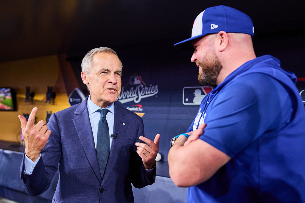 Canada's Prime Minister Mark Carney speaks speaks to Toronto Blue Jays manager John Schneider as he visits the Blue Jays during baseball's World Series media day, Thursday, Oct. 23, 2025, in Toronto,. (Sammy Kogan/The Canadian Press via AP)