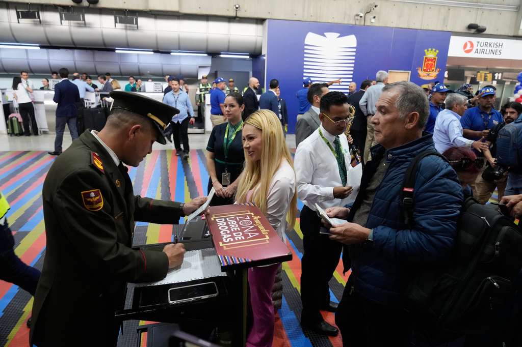 A National Guard officer checks passengers ID's prior to check in for a U.S.-bound commercial flight at Simon Bolivar International Airport in Maiquetia, Venezuela, Thursday, April 30, 2026, as direct air service between the United States and Venezuela resumes after seven years. (AP Photo/Ariana Cubillos)