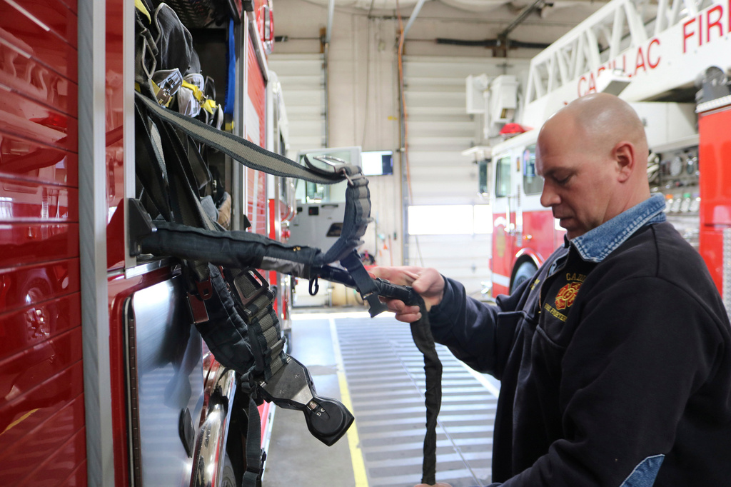 FILE - Cadillac firefighter/paramedic Joe Barron does an equipment check on an air pack on one of the trucks during some downtime, March 12, 2021 in Cadillac, Mich. (Rick Charmoli /The News via AP, file)